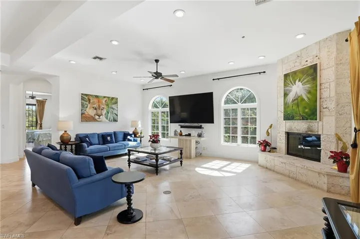 Living room with ceiling fan, a large fireplace, recessed lighting, and light tile patterned floors