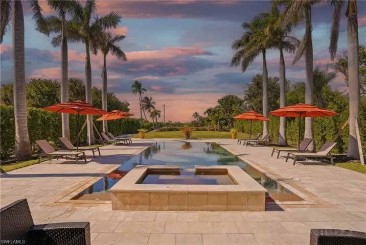 Pool at dusk with a patio and a pool with connected hot tub