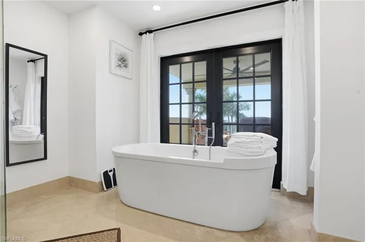 Bathroom featuring french doors, a freestanding bath, and recessed lighting
