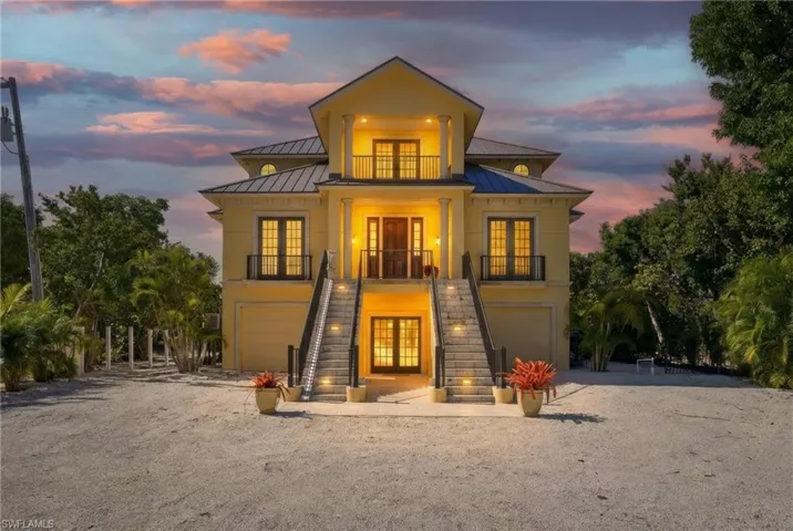 Back of property featuring french doors, a standing seam roof, an attached garage, and driveway