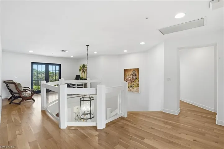 Hallway with light wood-style floors, recessed lighting, and an upstairs landing