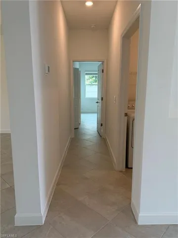Hall with light tile patterned floors and washer / dryer