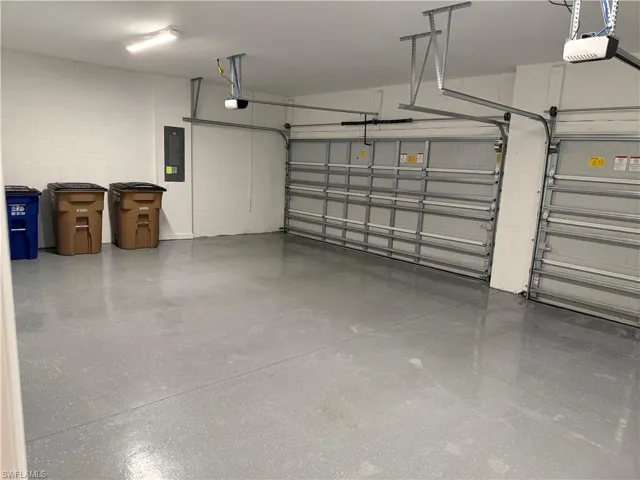 Garage with concrete block wall, electric panel, and a garage door opener
