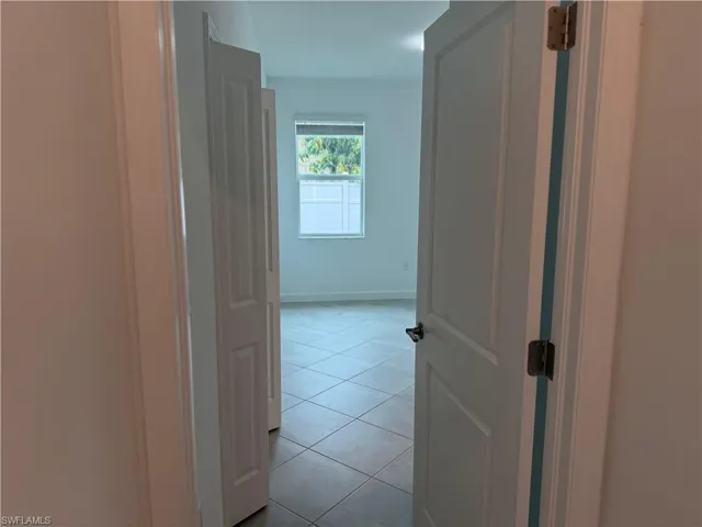 Bedroom 1 with light tile patterned floors and baseboards