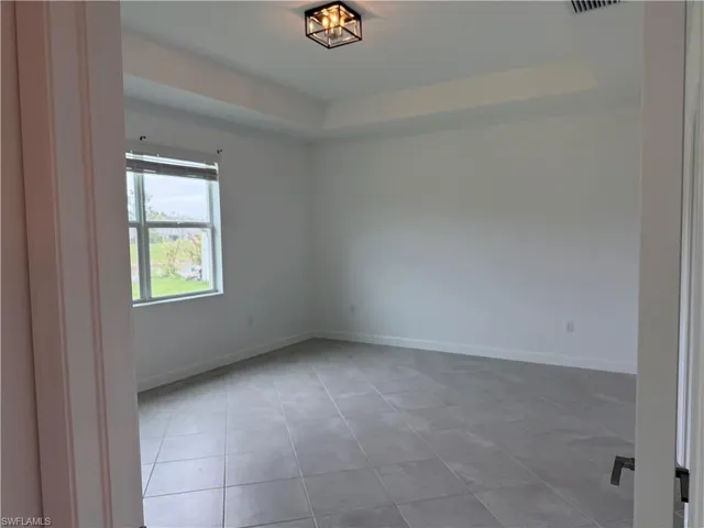 Primary room featuring a tray ceiling and light tile patterned flooring