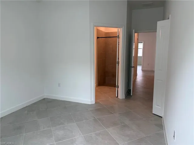 bedroom 1 featuring light tile patterned flooring and connected bathroom