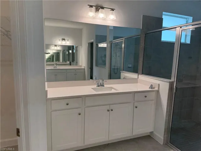 Full primary bath with a shower stall, vanity, and light tile patterned flooring