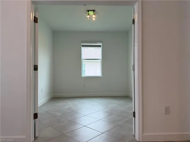 Spare room with baseboards and light tile patterned floors