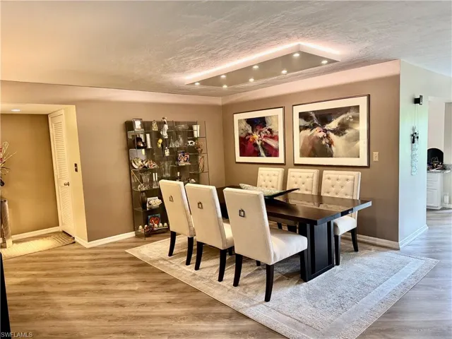 Dining space with a textured ceiling, wood-type flooring, and a tray ceiling