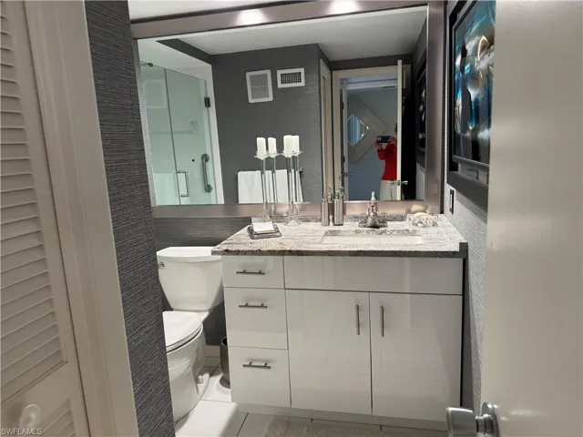 Bathroom with toilet, vanity, and tile patterned floors