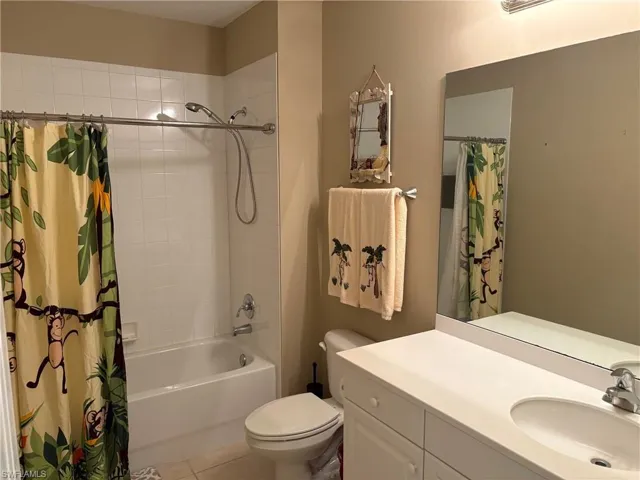 Bathroom featuring vanity, shower / bath combo, and light tile patterned floors