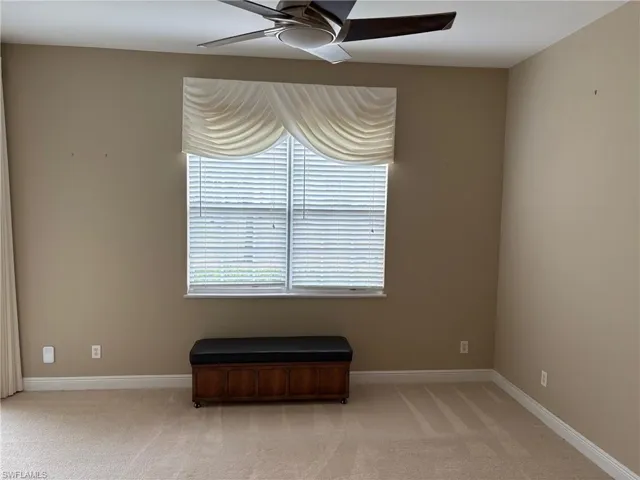 Empty room with light colored carpet and ceiling fan
