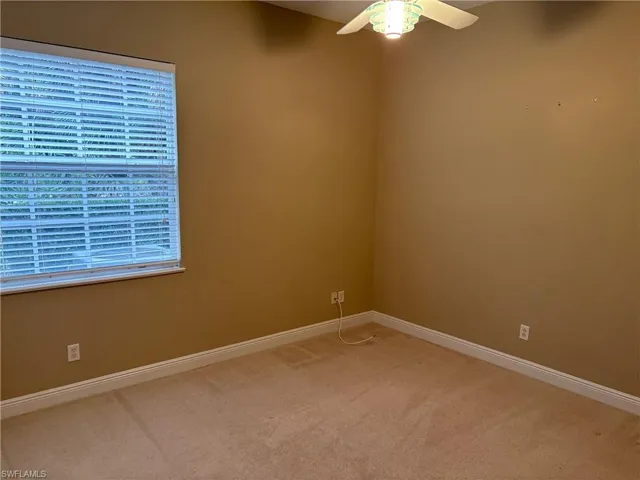 Empty room featuring a ceiling fan and light carpet
