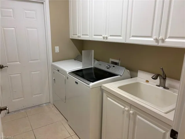 Laundry room featuring cabinet space, separate washer and dryer, and light tile patterned flooring