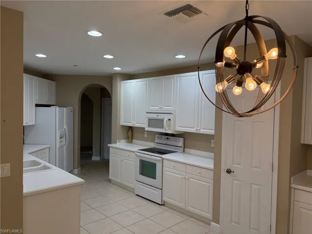 Kitchen featuring white appliances, light countertops, white cabinets, and recessed lighting
