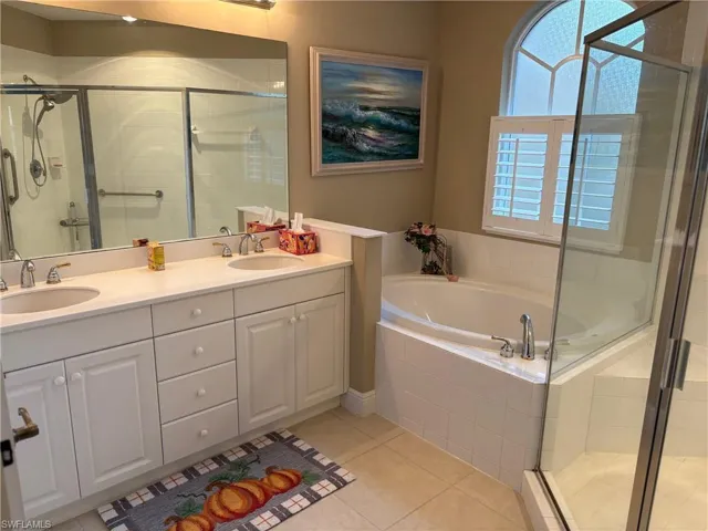 Full bathroom with a shower stall, double vanity, light tile patterned floors, and a bath
