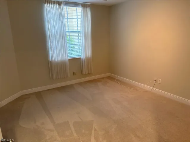 Empty room with light colored carpet and baseboards