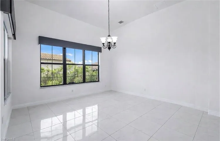 Empty room with suspended lighting, light tile patterned floors, and lofted ceiling