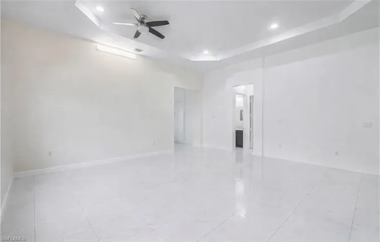 Unfurnished room with a raised ceiling, ceiling fan, and recessed lighting