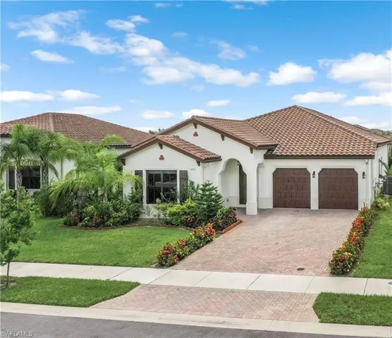 Mediterranean / spanish house featuring decorative driveway, a front yard, stucco siding, and a tiled roof