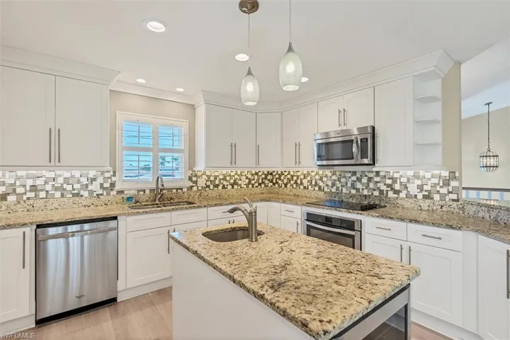 Kitchen featuring white cabinetry, sink, light stone countertops, and appliances with stainless steel finishes