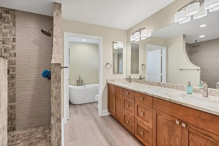 Bathroom with hardwood / wood-style flooring, vanity, and independent shower and bath