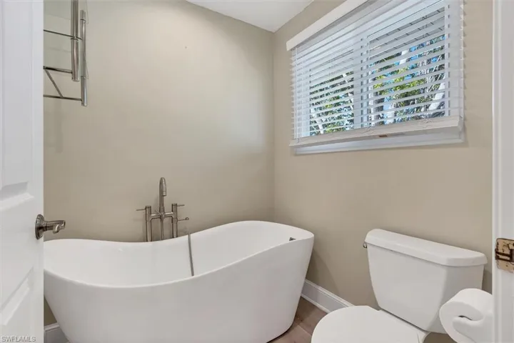 Bathroom featuring hardwood / wood-style floors, toilet, and a tub