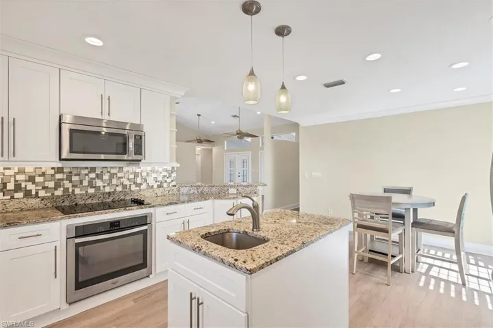 Kitchen with white cabinetry, decorative backsplash, ceiling fan, and appliances with stainless steel finishes