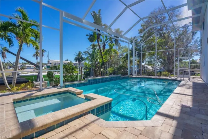 View of swimming pool featuring glass enclosure, an in ground hot tub, and a patio