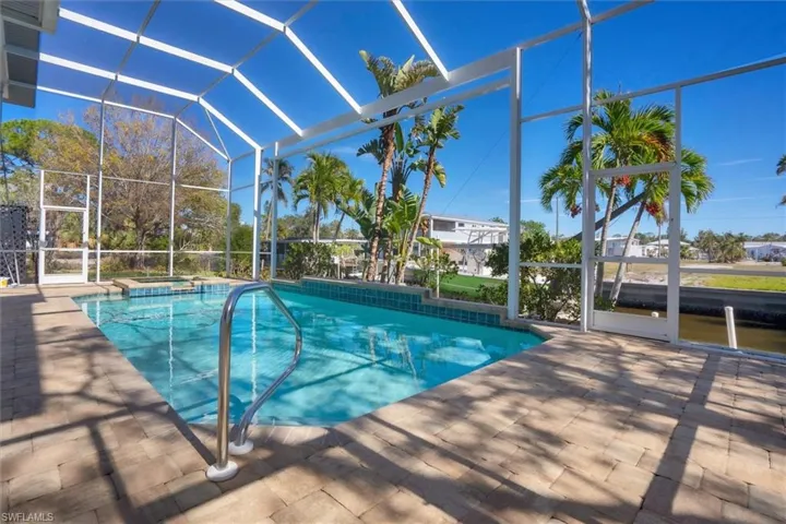 View of pool featuring glass enclosure, an in ground hot tub, and a patio
