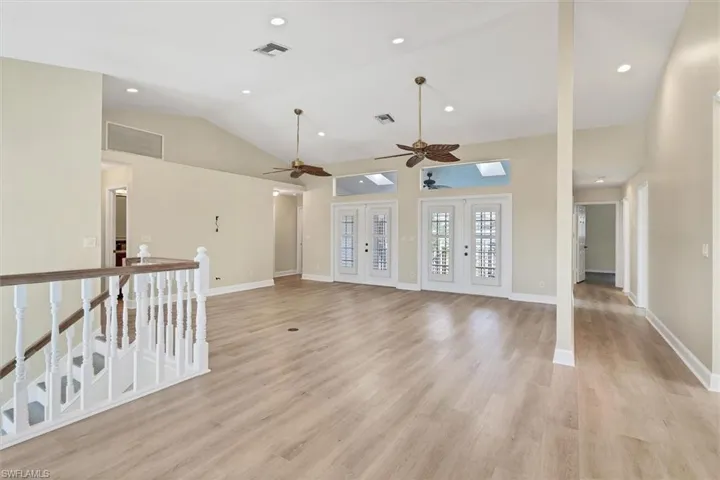 Unfurnished living room with french doors, light hardwood / wood-style floors, vaulted ceiling, and ceiling fan