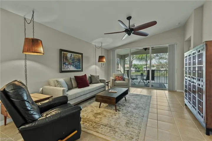 Living room with light tile patterned floors, ceiling fan, and lofted ceiling