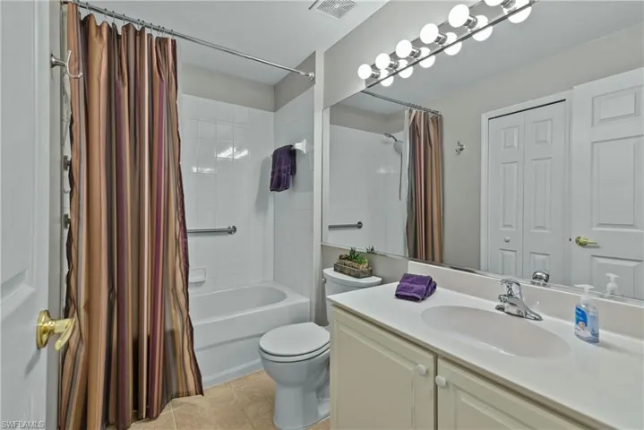 Full bathroom with shower / bath combo with shower curtain, tile patterned flooring, vanity, and toilet