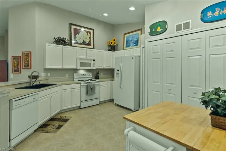 Kitchen with kitchen peninsula, white cabinetry, white appliances, and sink