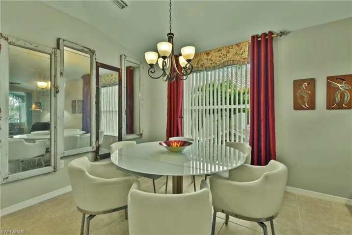 Tiled dining space featuring plenty of natural light, a chandelier, and lofted ceiling