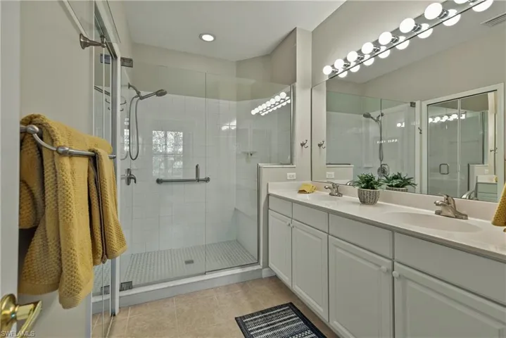 Bathroom featuring tile patterned flooring, vanity, and a shower with shower door