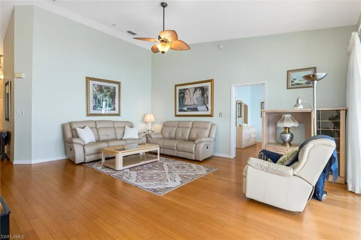 Living area with bamboo wood floors, a ceiling fan, and vaulted ceiling