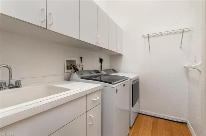 Interior laundry room featuring cabinets, utility sink, washer, dryer and utility storage closet