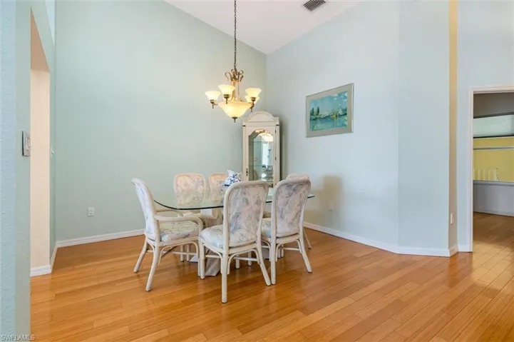 Dining room featuring vaulted ceiling, hanging lights, and wood floors