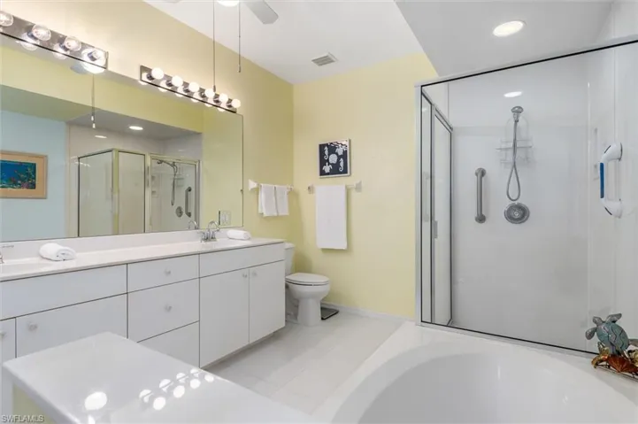 Primary ensuite bathroom with dual vanity, garden tub, walk-in shower and linen closet. Ceramic tile floor.