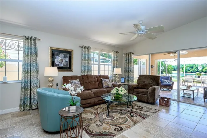 Living room featuring lofted ceiling, ceiling fan, and light tile floors