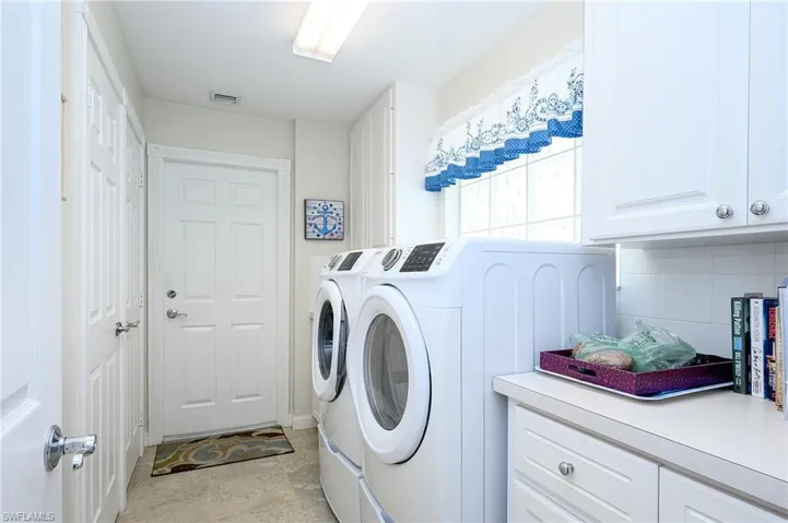 Laundry room with newer washer and dryer, cabinets, and light tile floors