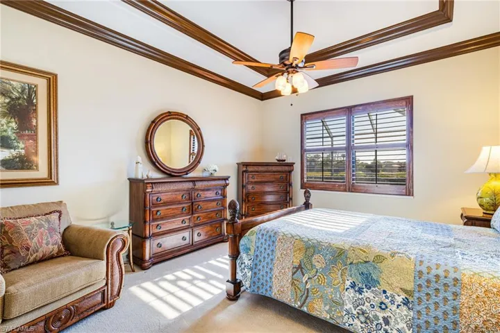 Primary Bedroom with crown molding, ceiling fan, carpet flooring, and a raised ceiling