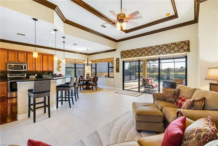 Living area with a ceiling fan, suspended lighting, crown molding, and light tile patterned flooring