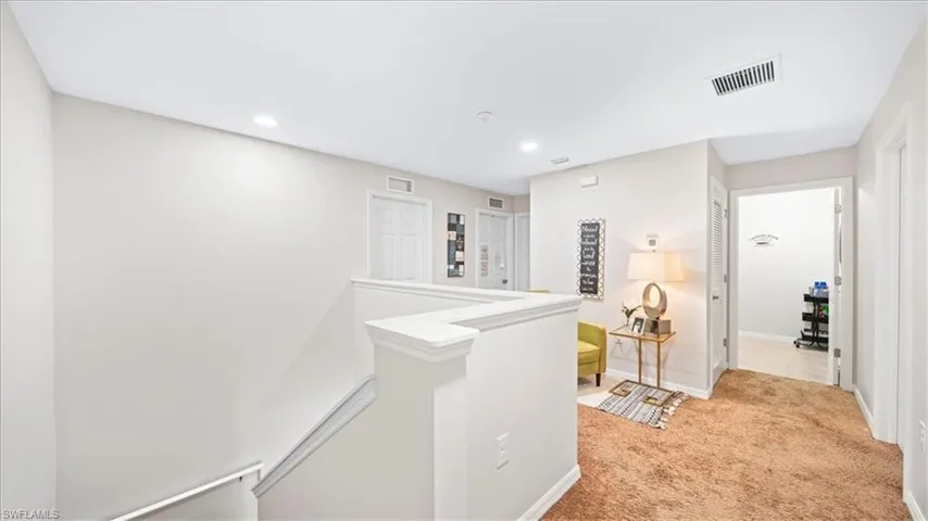 Hallway featuring an upstairs landing, light colored carpet, and recessed lighting