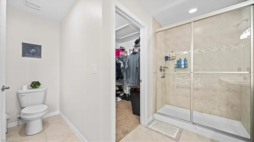 Full bathroom featuring a shower stall, a spacious closet, and light tile patterned floors