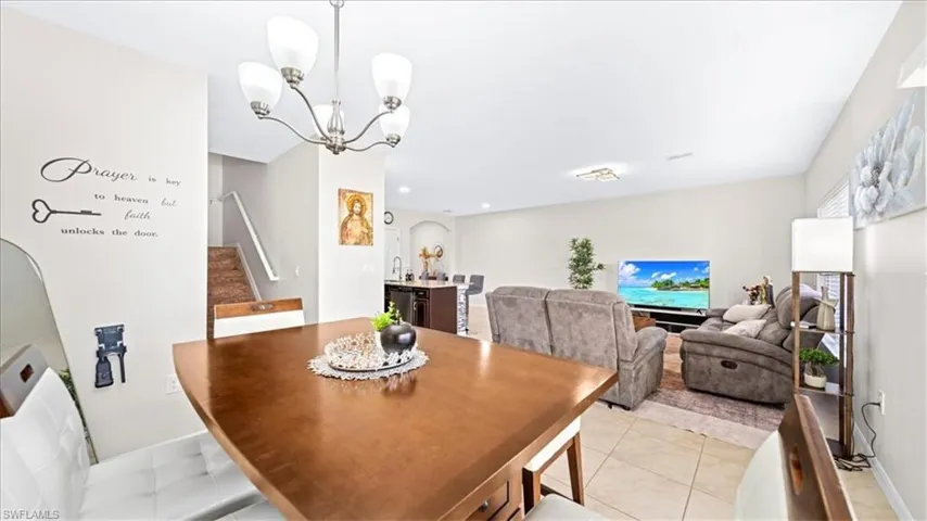 Dining space featuring arched walkways, stairs, light tile patterned floors, and a chandelier