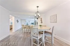 Dining room featuring baseboards, wood finished floors, a chandelier, and ornamental molding