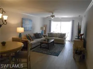Living area with wood finished floors, a ceiling fan, crown molding, and a chandelier