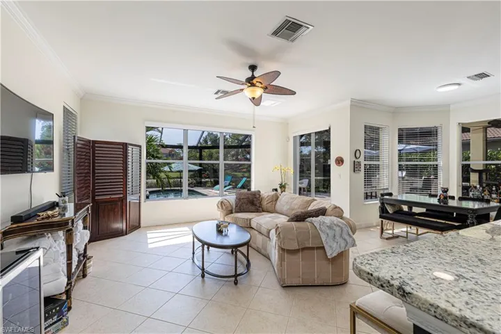 Living room featuring a healthy amount of sunlight, ornamental molding, ceiling fan, and light tile floors